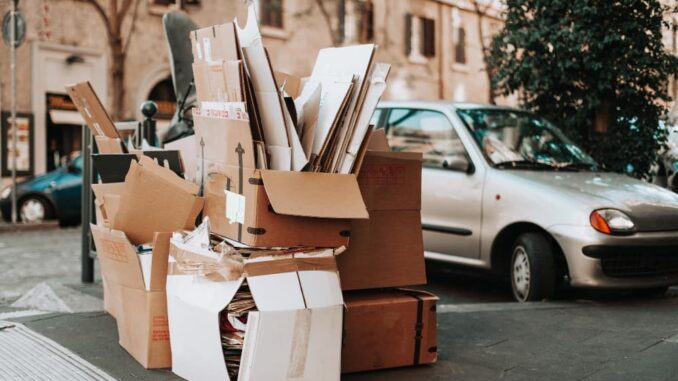 Des boîtes en carton empilées sur un trottoir, un signe d'accumulation